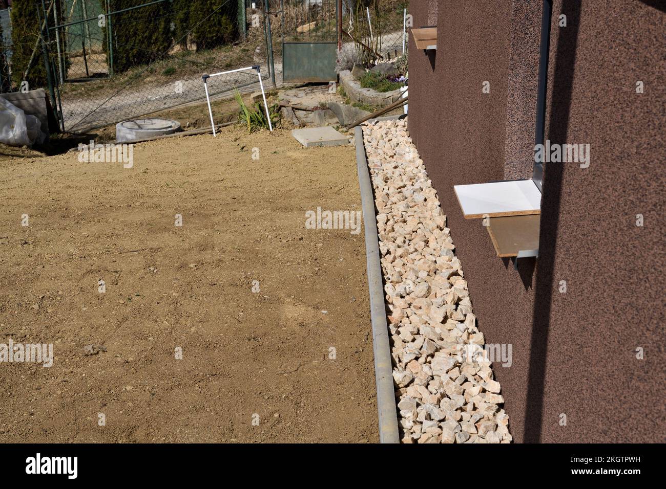 Ein Abflussweg aus dekorativen Steinen um die Wand des Hauses Stockfoto