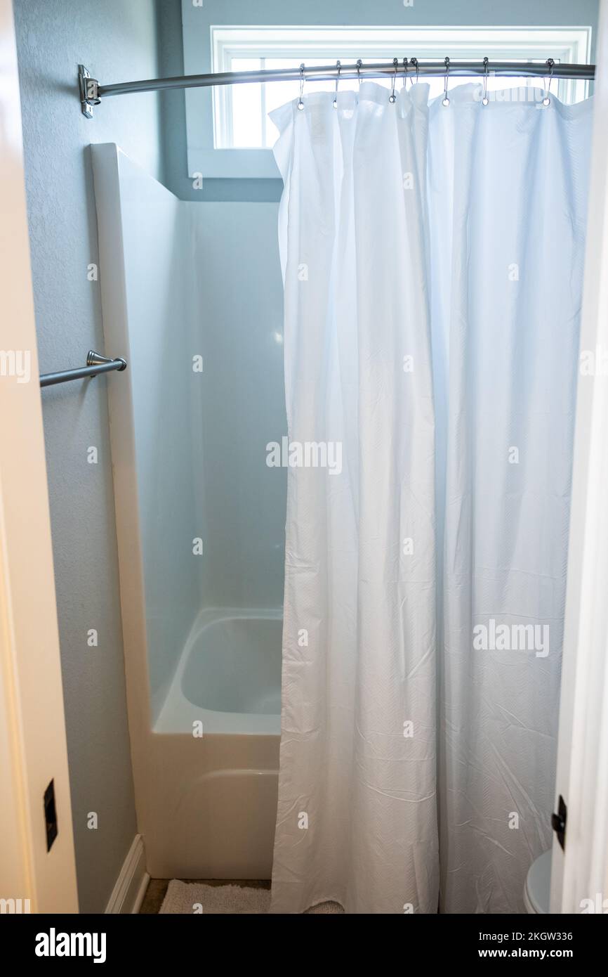 Kleines Bad mit Badewannen-Duscheinsatz und weißem Duschvorhang Stockfoto