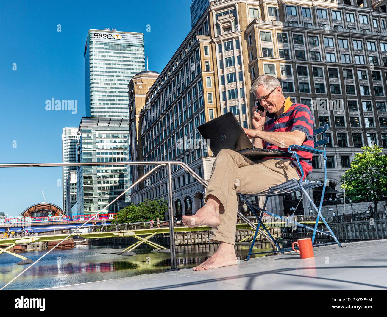 Große/kleine Unternehmen entspannter, erwachsener Mann, der draußen auf seinem Hausboot-Barge-Büro sitzt und zu Hause auf seinem Laptop Canary Wharf London E14 arbeitet Stockfoto