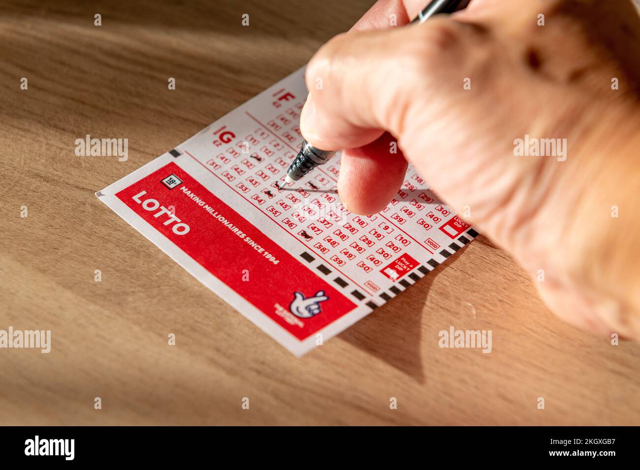 Nach London. GROSSBRITANNIEN - 11.20.2022. Eine Person, die die Spielnummer für einen Lotto-Gutschein auswählt. Stockfoto