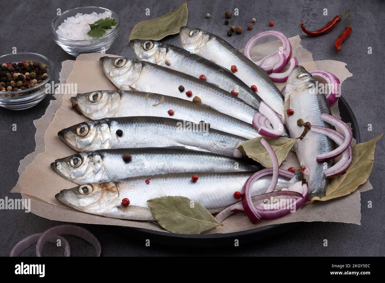 Mehrere eingelegte Heringe mit Gewürzen auf Pergamentpapier Stockfoto