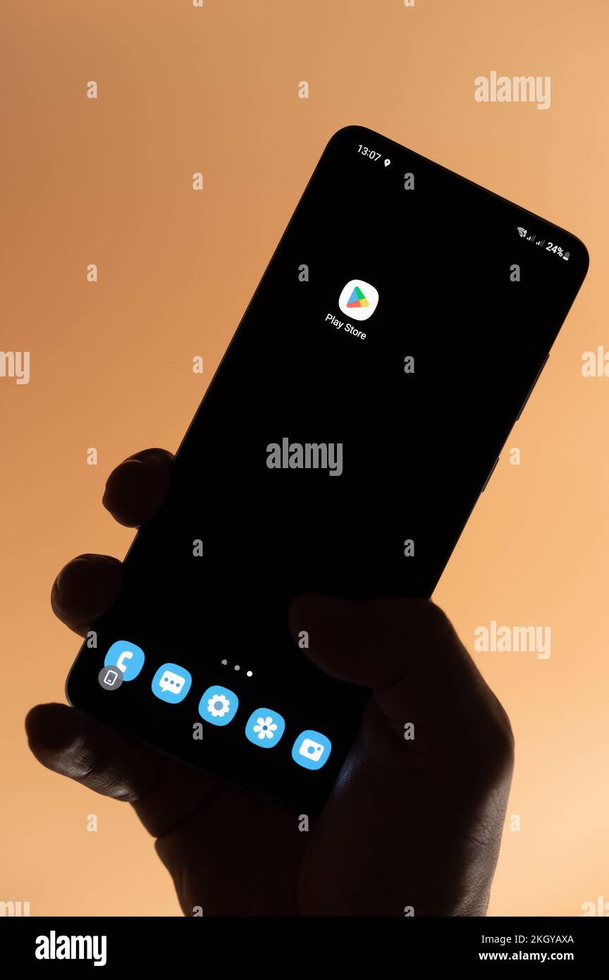 New york, USA - 4. November 2022: Öffnen sie die google Play Store App auf einem Smartphone, indem Sie die Hand isoliert auf braunem Hintergrund halten Stockfoto