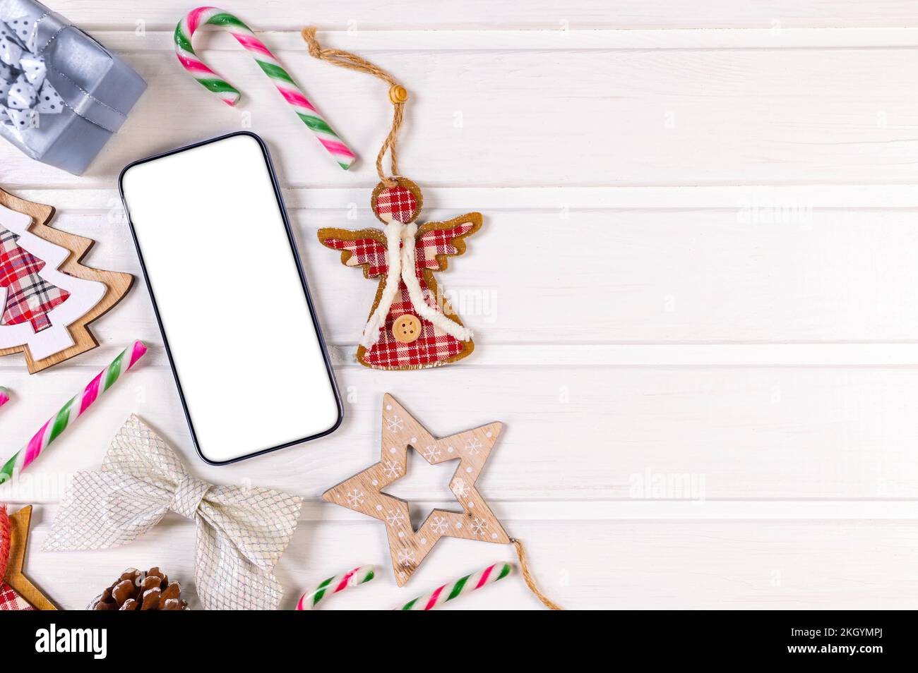 Smartphone-Modell mit rustikalen Weihnachtsdekorationen auf dem Holztisch für die App-Präsentation. Blick von oben Stockfoto