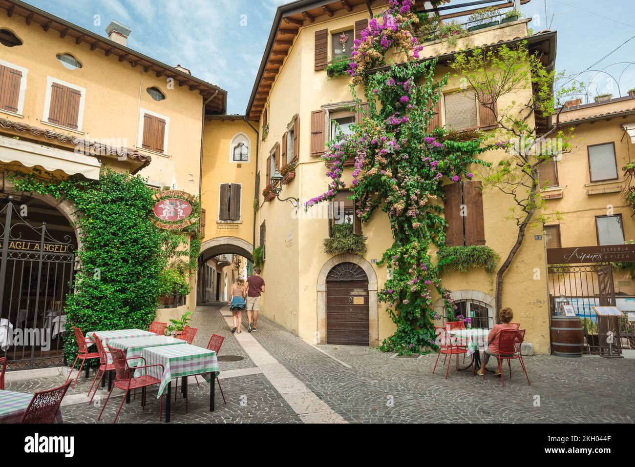 Italienische Seenstadt, Blick im Sommer auf ein junges Paar, das durch eine kleine malerische piazza im Dorf Gardone Sopra, Gardasee, Italien spaziert Stockfoto