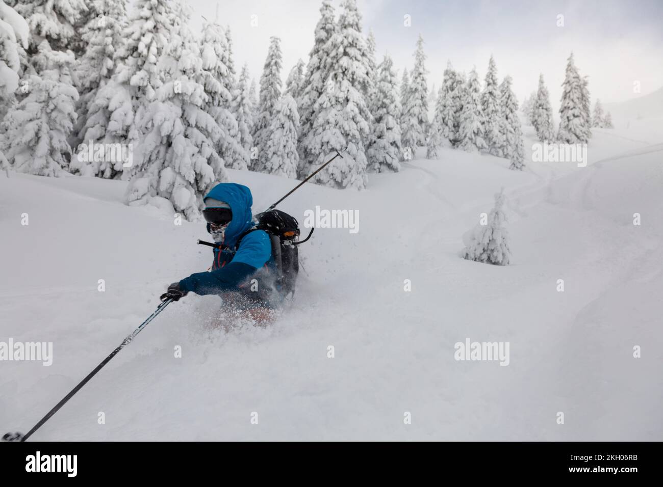 Männlicher Skifahrer, geschwungen und Bremsen, die losen tiefen Schnee auf der Freeride-Steigung spritzen. Freeride, Wintersport im Freien Stockfoto
