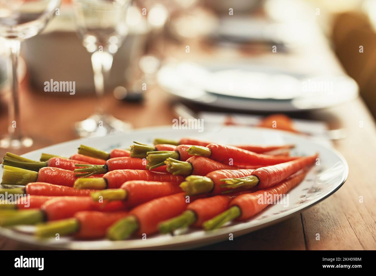 Thanksgiving, Karotten und Essen mit einem Teller Gemüse auf einem Esstisch für Tradition in einem leeren Raum. Braten, Essen und Ernährung mit einem Mittagessen Stockfoto