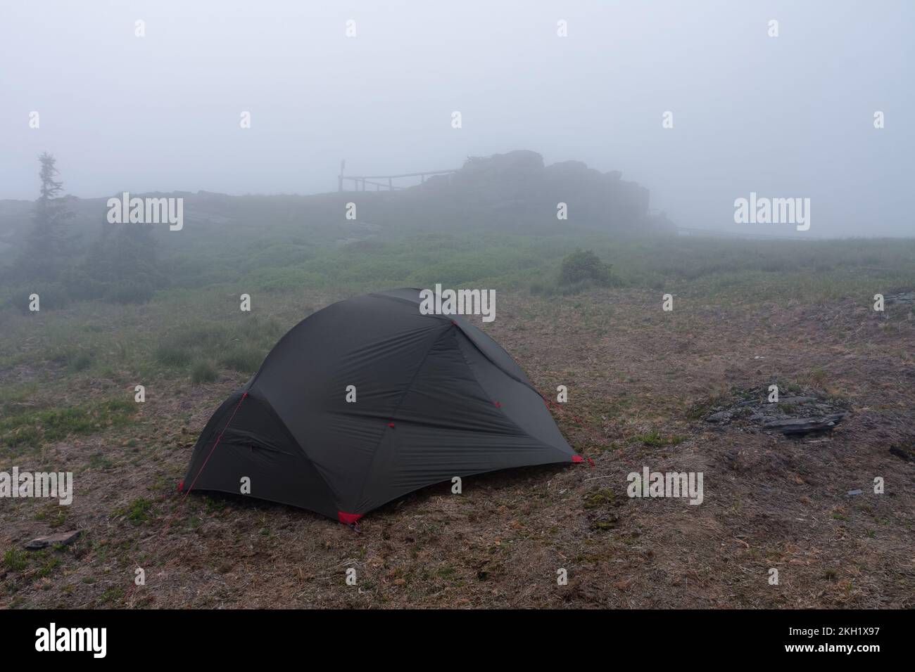 Grünes, leichtes, freistehendes Zelt für 2 Personen auf einem Hügel im Gras am Abend nach dem Regensturm. Jesenik-Berge, Tschechische Republik Stockfoto