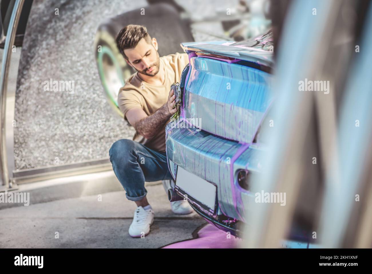 Fokussierter automatischer Detaillierer, der das Rücklicht eines Fahrzeugs wäscht Stockfoto