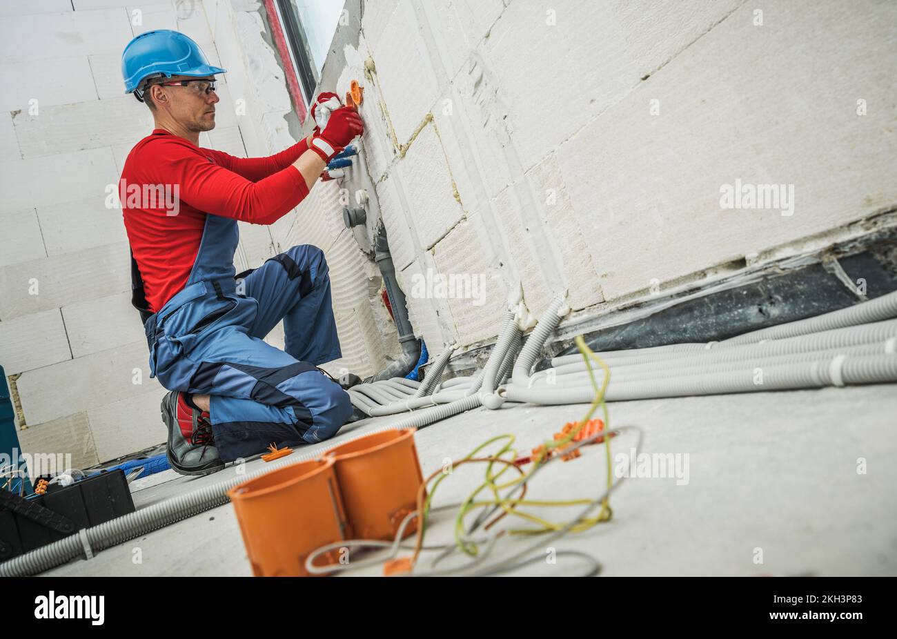 Professioneller Elektriker, der Steckdosen in der Wand des Wohngebäudes auf der Baustelle installiert. Thema: Stromversorgung Im Haushalt. Stockfoto