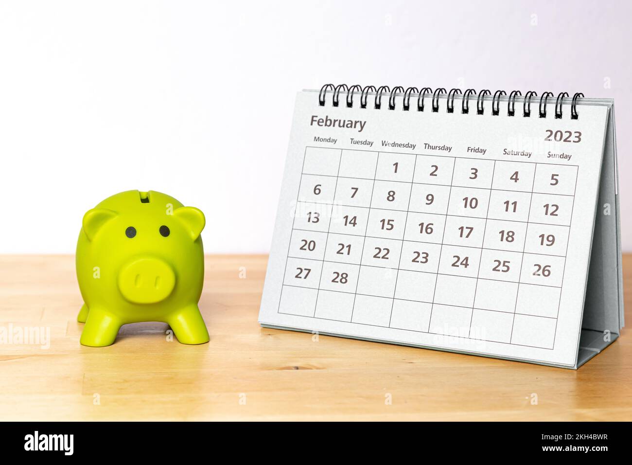 Kalender vom 2023. Februar und Sparschwein auf einem Holztisch Stockfoto