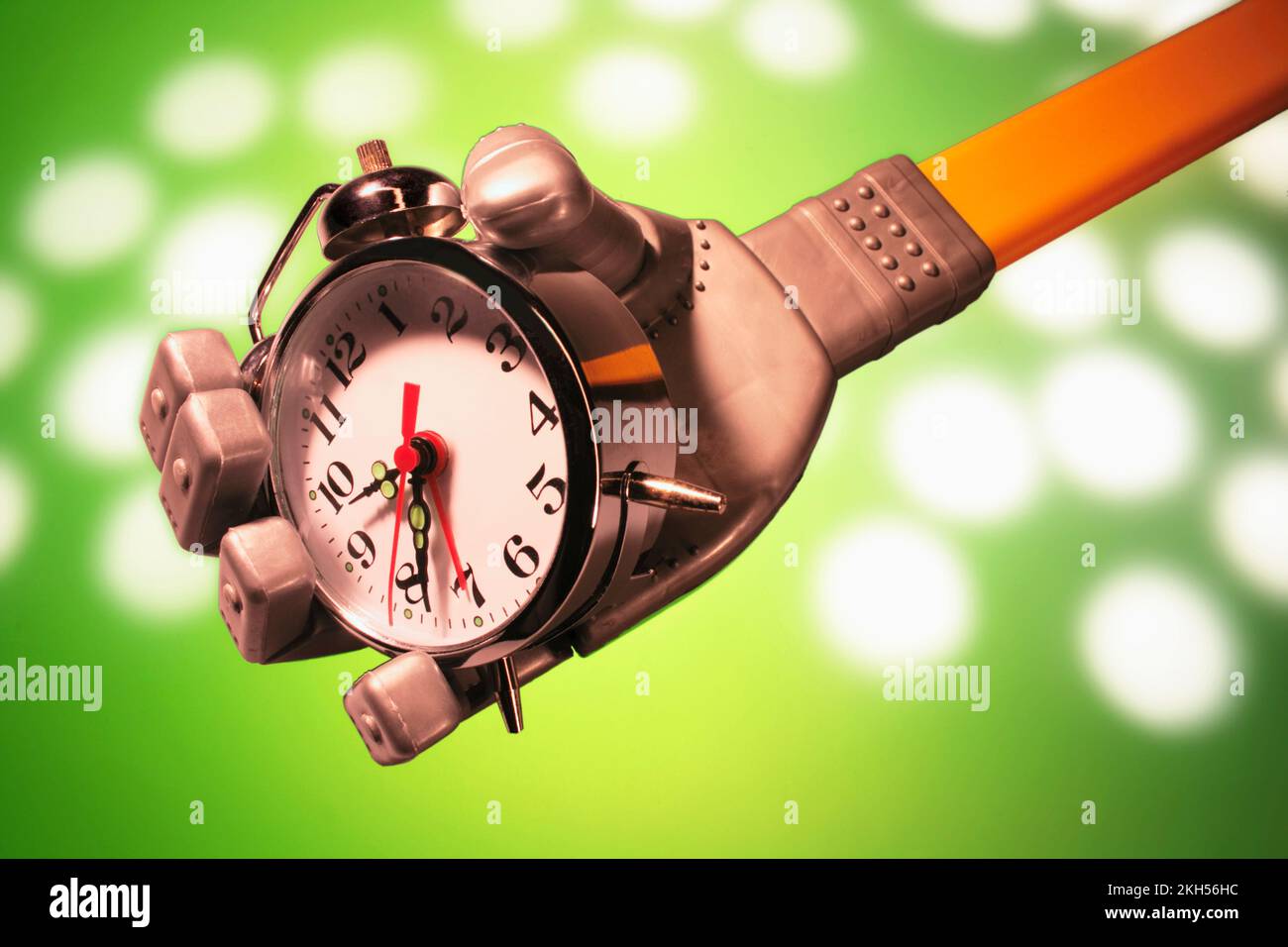 Roboterhand mit Wecker auf grünem Hintergrund Stockfoto