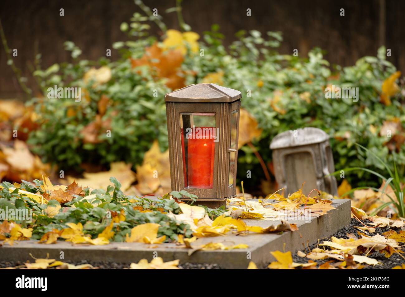 Nahaufnahme einer Grablaterne auf einem mit Herbstblättern bedeckten Grab Stockfoto