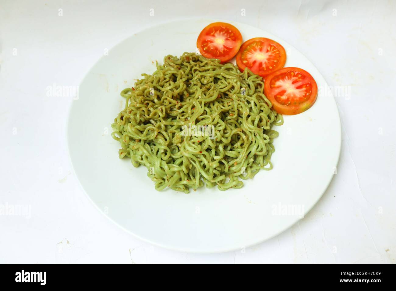 Grüne Nudeln oder Spinatpasta, Zucchini rohe vegane Pasta Dip und Tomaten auf dem Teller. Stockfoto