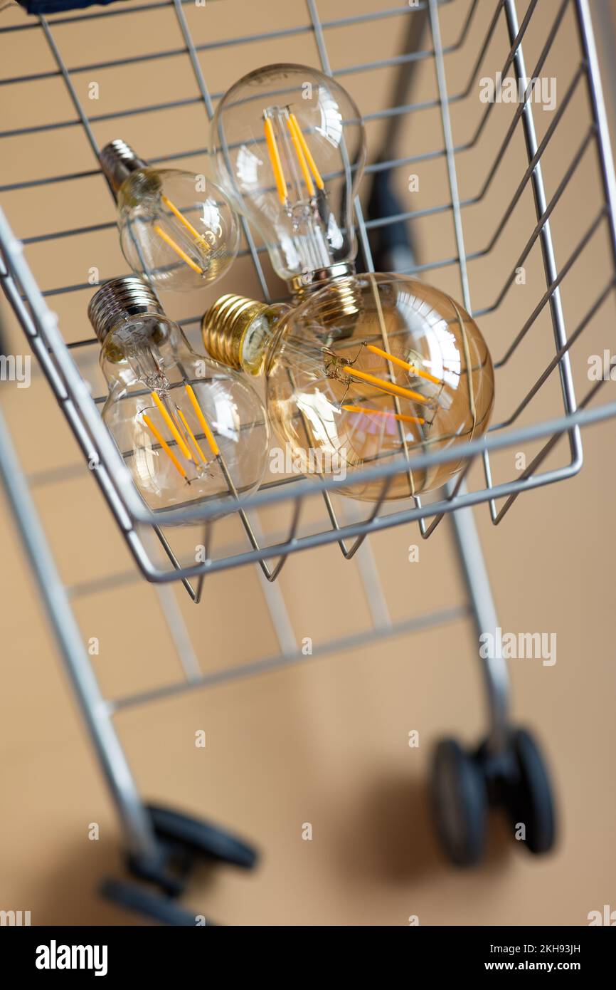 Kauf von Elektrizität. Elektrische Lampen im Einkaufswagen. Verbrauch und Energierückzahlung. Krise im Energiesektor. Stockfoto