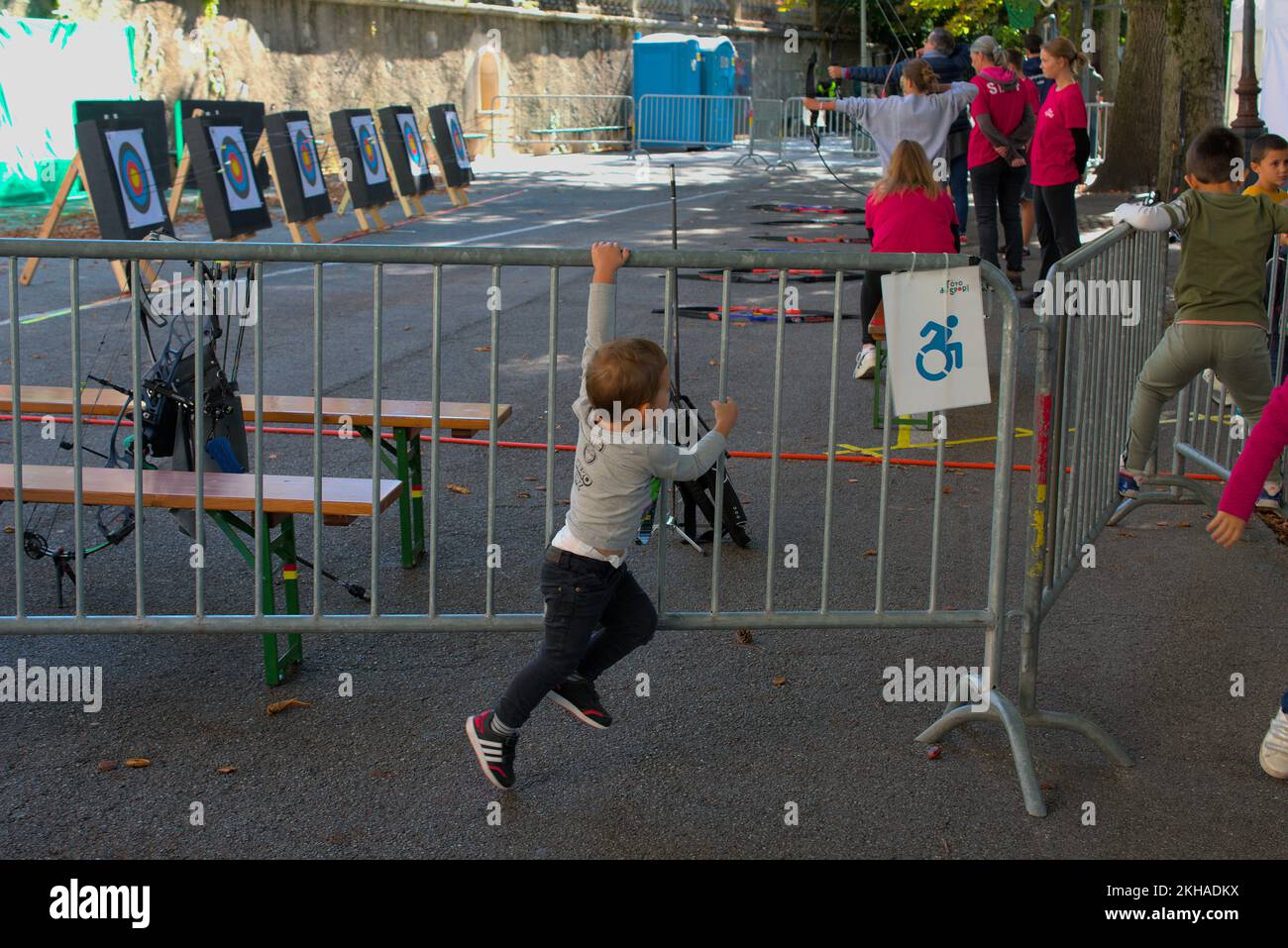 Ein junger Junge hängt in einer Barrikade, während im Hintergrund Bogenschießen-Kurse stattfinden Stockfoto