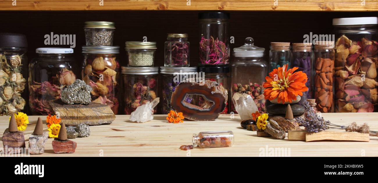 Meditationsaltar mit Steinkristallen und Blumen. Krüge mit Kräutern Stockfoto