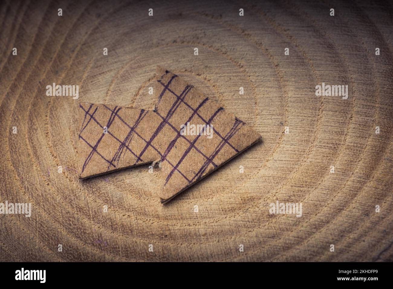 Pfeil-Symbol auf Stück Holz aus braunem Papier schneiden Stockfoto