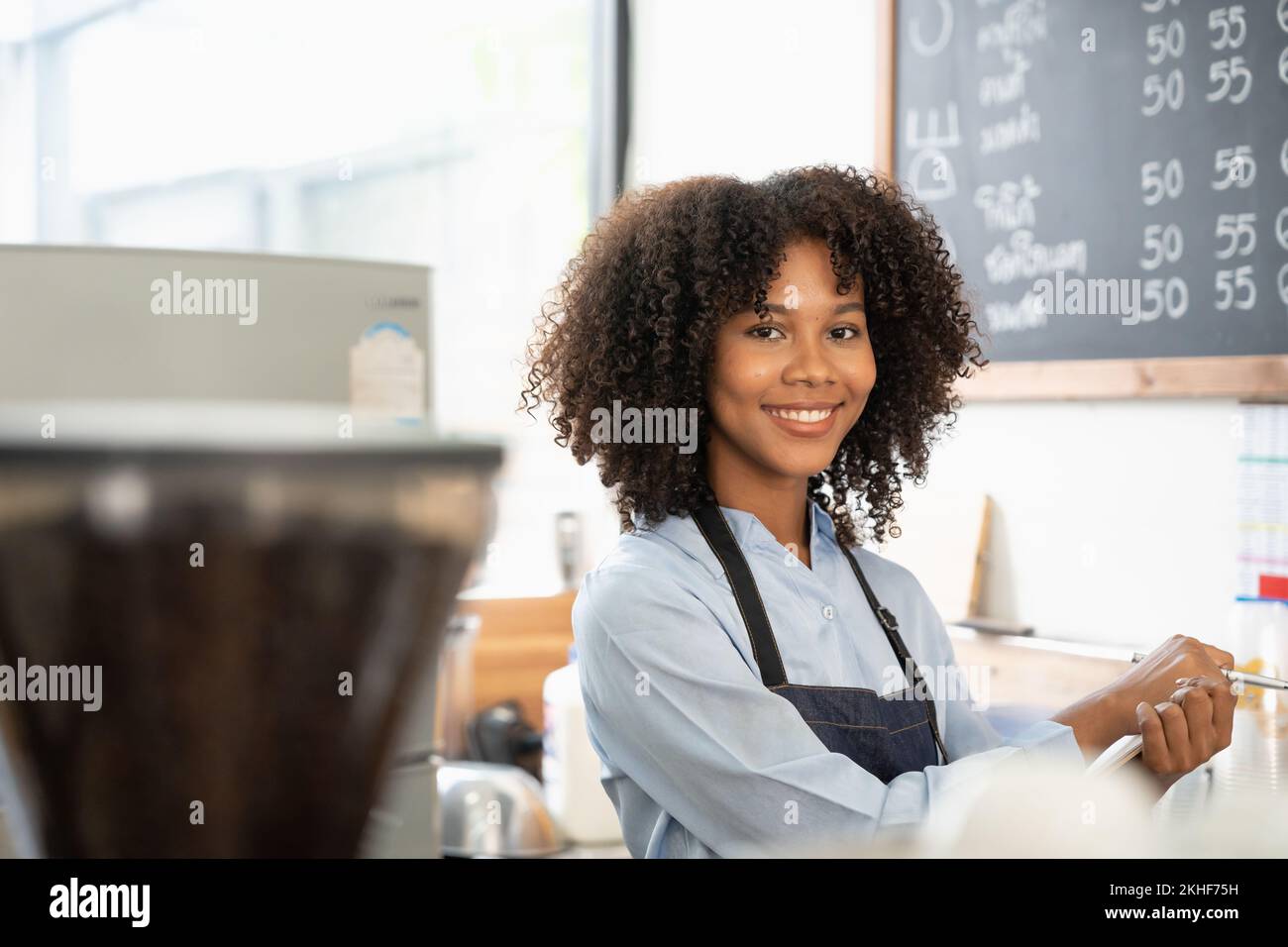 Porträt einer lächelnden jungen afroamerikanischen Kellnerin mit Schürze, die bereit ist, die Bestellung aufzunehmen Stockfoto