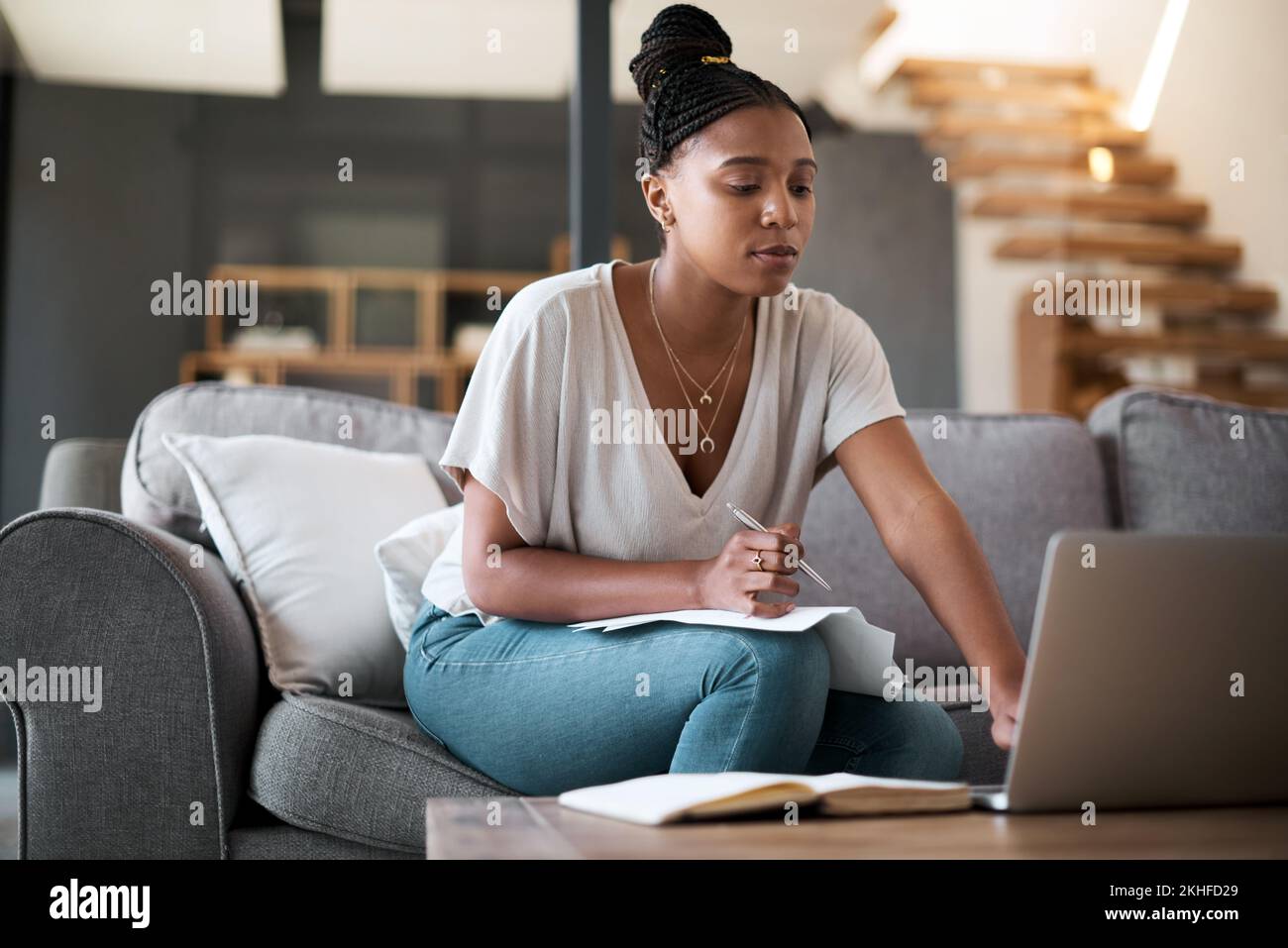 Finanzen, Laptop und schwarze Frau, die ein Haushaltsbudget für Rechnungen, Ersparnisse oder Geldverwaltung auf dem Sofa im Wohnzimmer verfasst. Papierkram, Inflation und Afrika Stockfoto