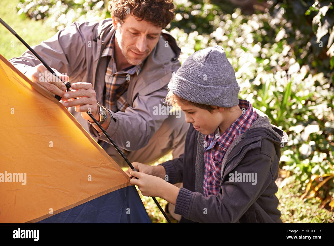 Outdoor-Abenteuer mit Dad. Ein süßer kleiner Junge, der seinem Vater hilft, draußen ein Zelt zu errichten. Stockfoto