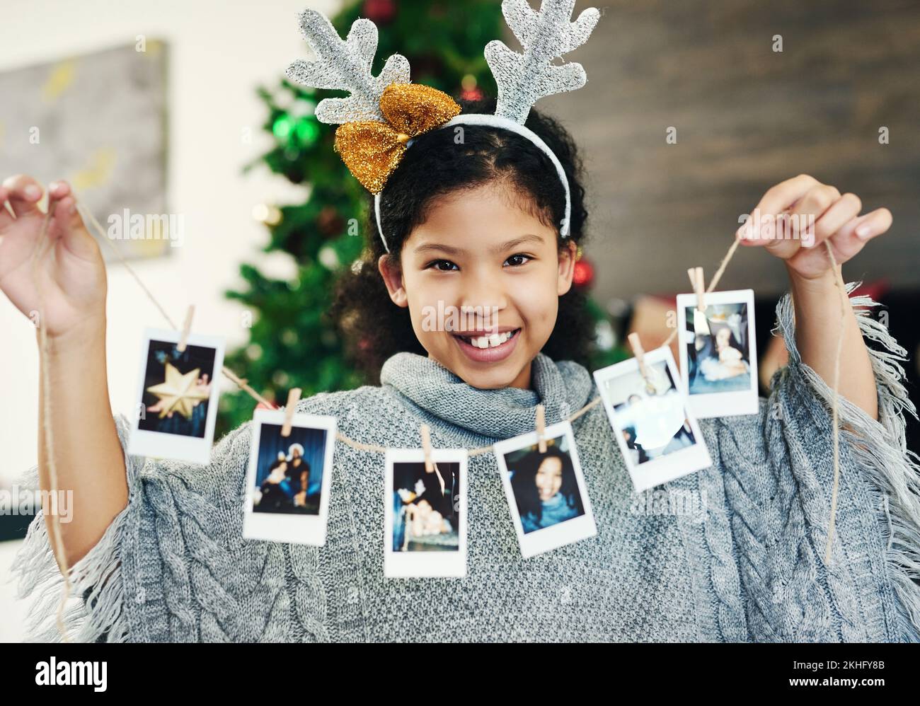 Weihnachten, Feier und Mädchen mit polaroid zur Dekoration, glücklich und zeigen Fotos im Haus. Lächeln, Aufregung und Porträt eines Kindes mit Bildern Stockfoto