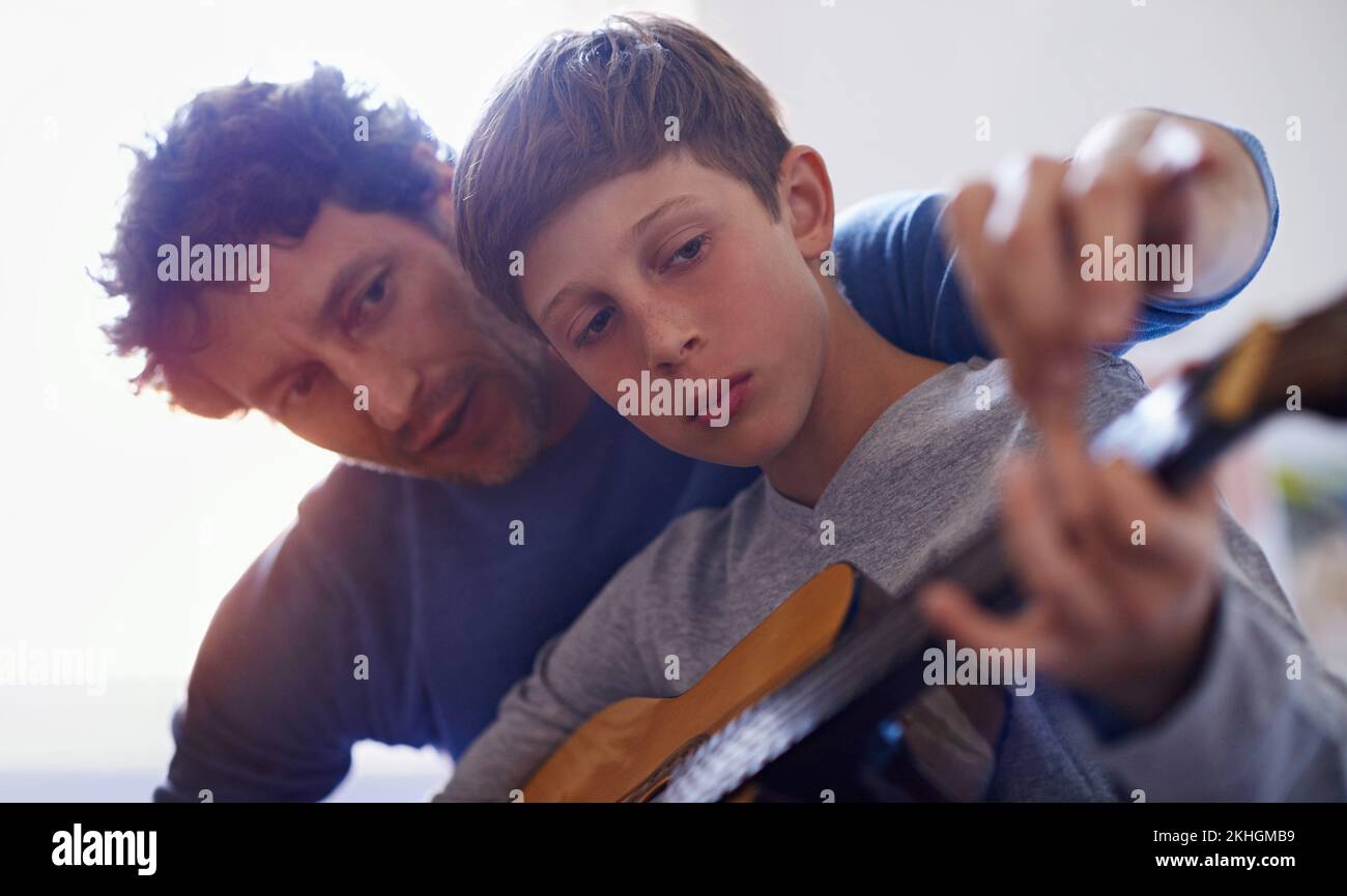 Perfekte Bindungsaktivität. Ein Junge, der Gitarre spielt, von seinem Vater. Stockfoto