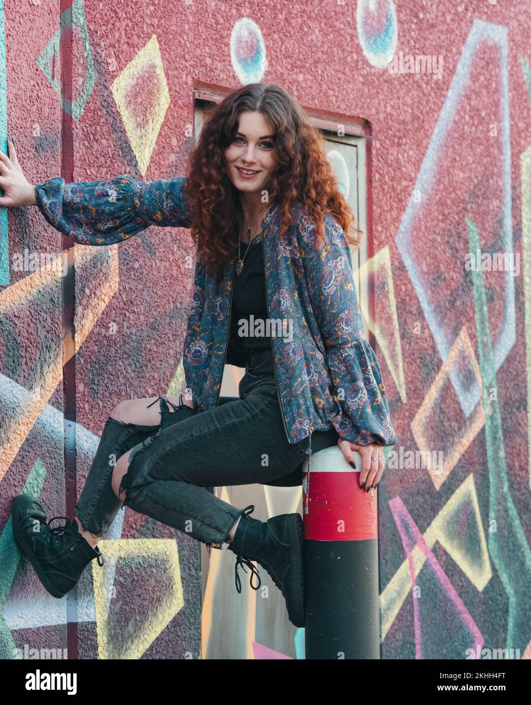 Eine Frau hält sich an eine bemalte Wand. Stockfoto