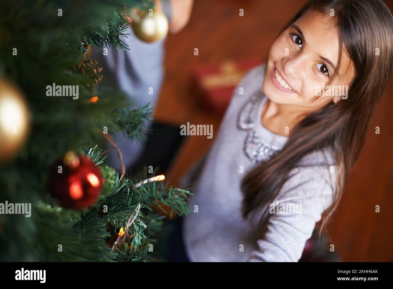 Rate mal, wer dieses Jahr dekoriert hat. Porträt eines kleinen Mädchens, das an einem weihnachtsbaum steht. Stockfoto