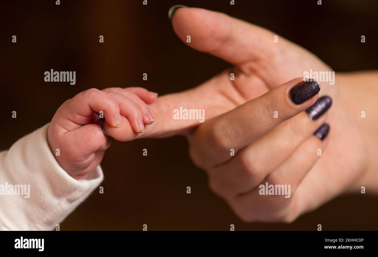 Dateifoto von 23/01/16 eines Babys, das den Finger seiner Mutter hält, da etwa drei von 10 (31 %) Alleinerziehenden aufgrund steigender Lebensmittelpreise auf Mahlzeiten verzichtet haben. Stockfoto