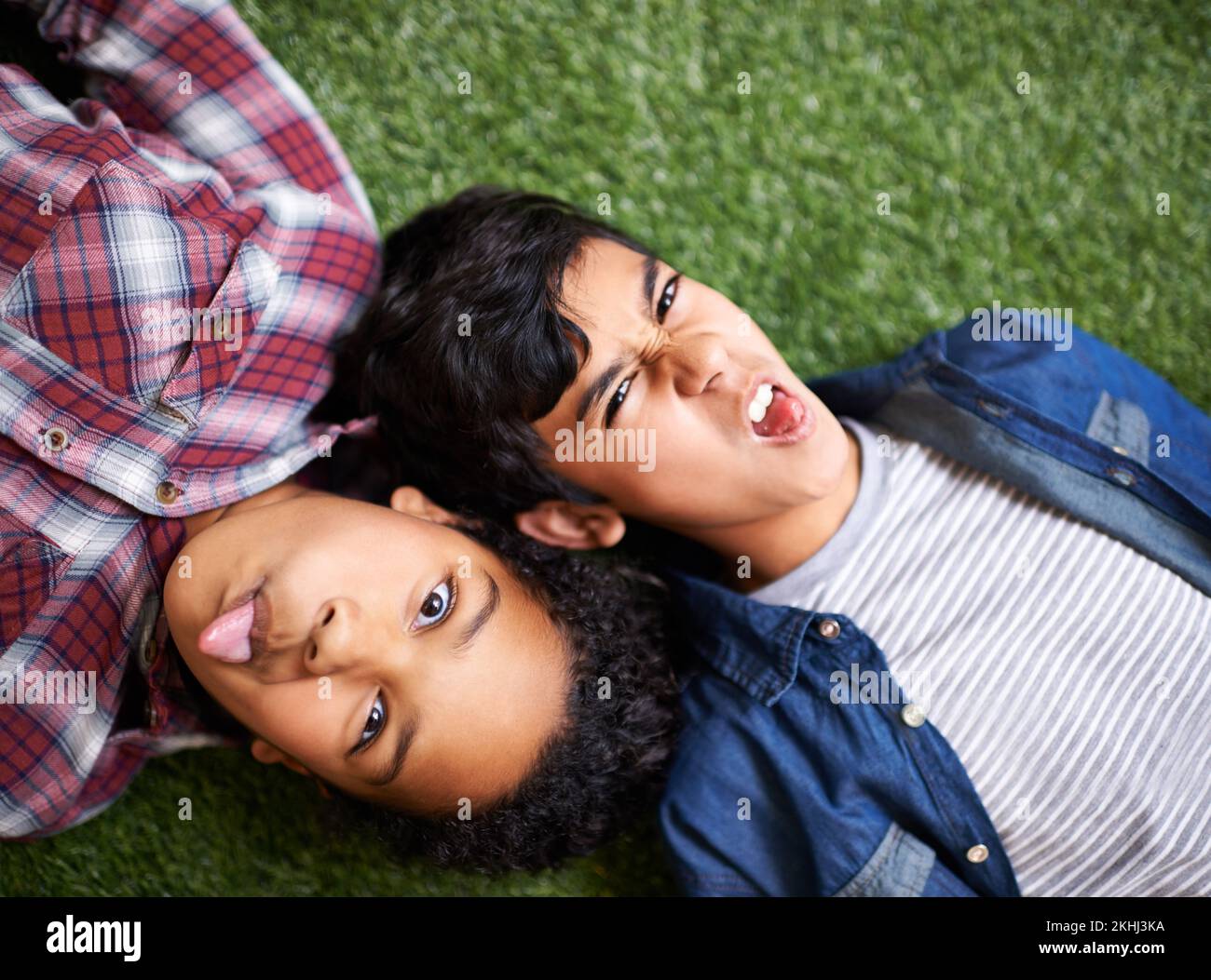 Ein bisschen Geschwister-Dummheit. Ein Bruder und eine Schwester, die auf dem Rasen liegen. Stockfoto