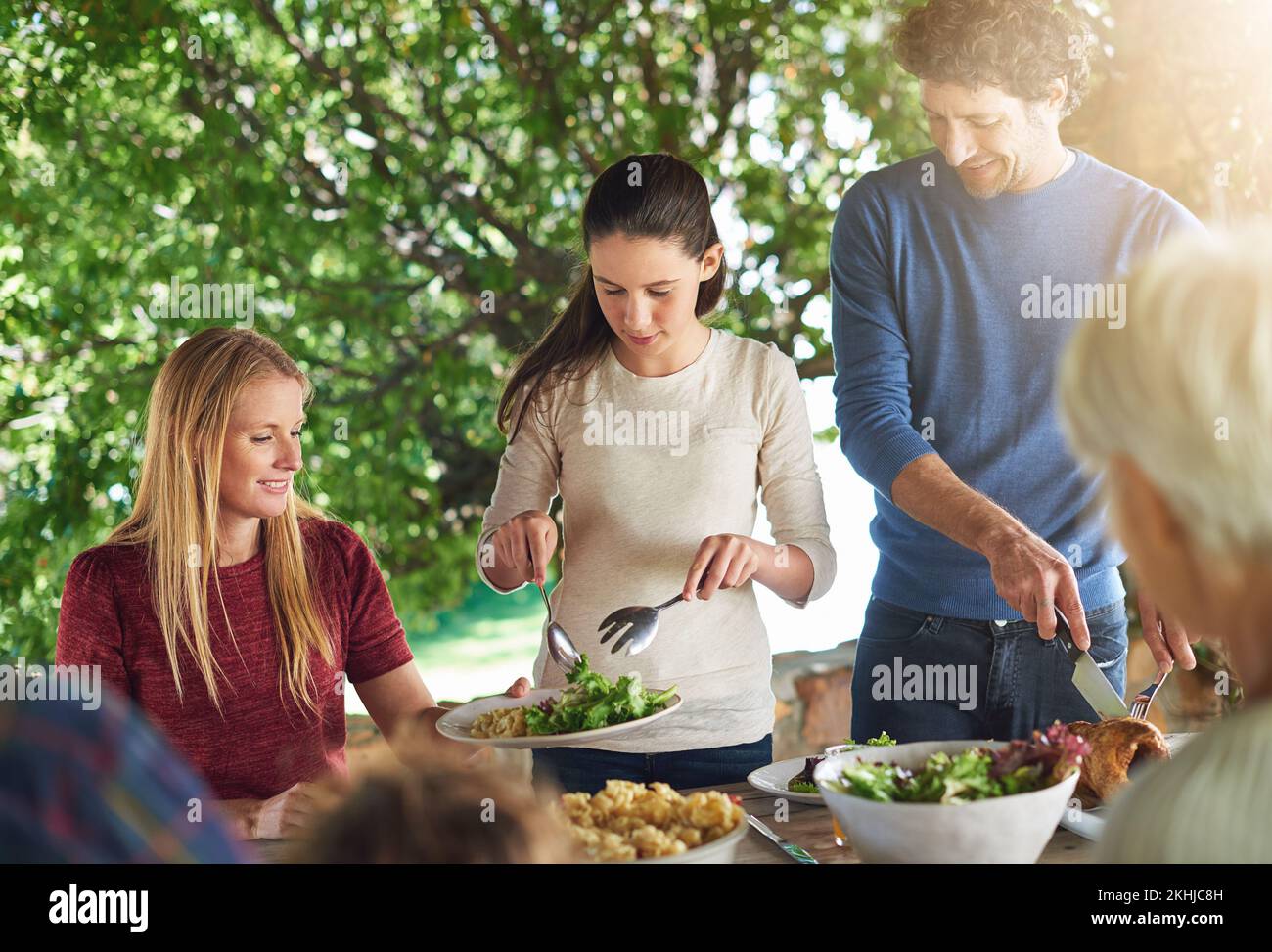 Ich Sorge dafür, dass sie genug Grünzeug bekommt. Eine Familie, die sich auf ein gemeinsames Mittagessen im Freien vorbereitet. Stockfoto
