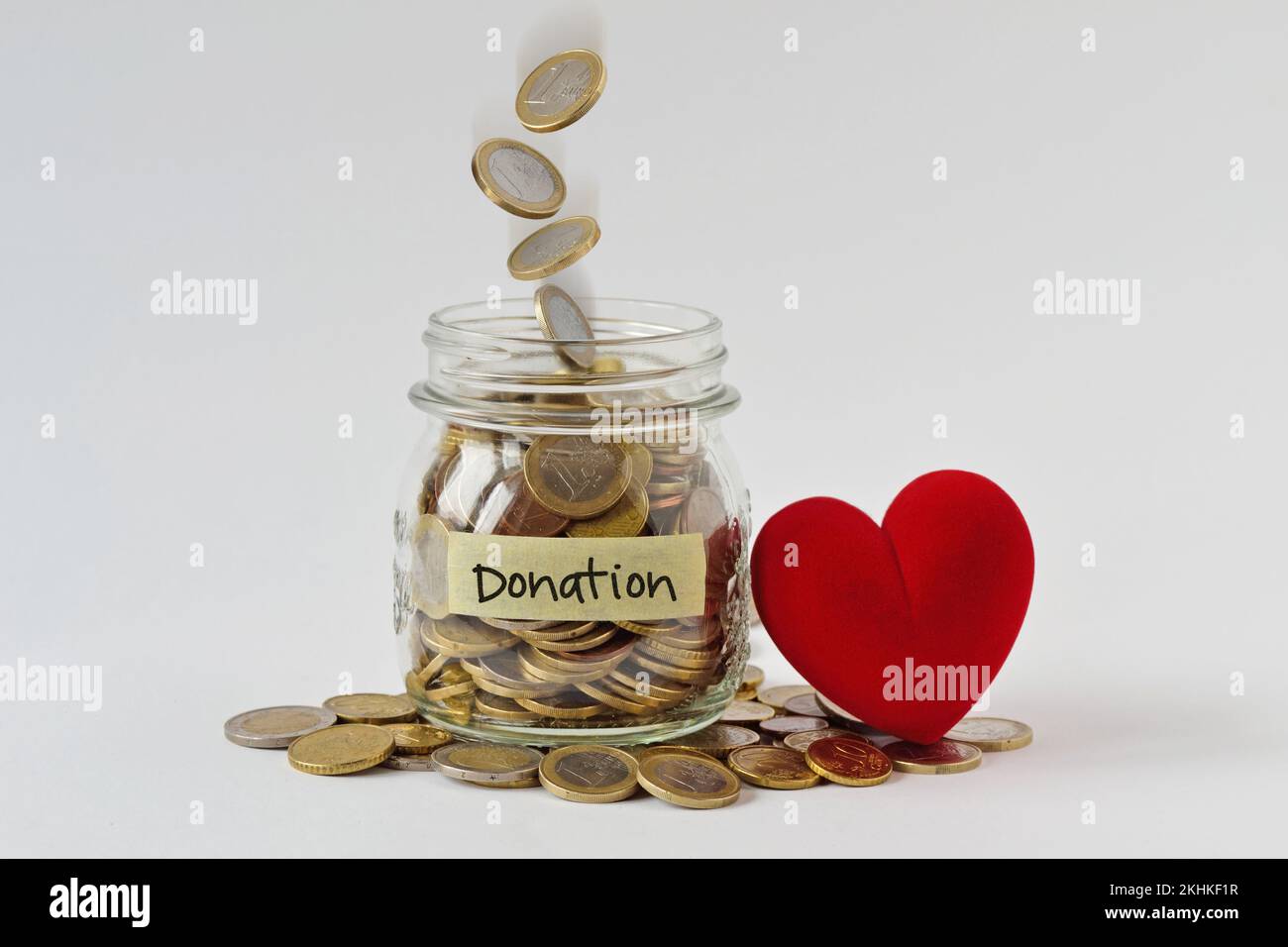 Geldbehälter voller Münzen mit Spendenetikett und Herz - Wohltätigkeits- und Spendenkonzept Stockfoto