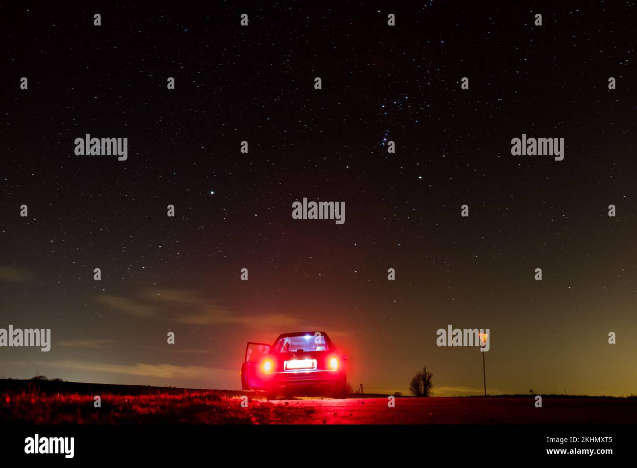 Ein Auto auf dem Hintergrund der Sterne mit Nachthimmel, glänzende Galaxie, rote Rücklichter Stockfoto