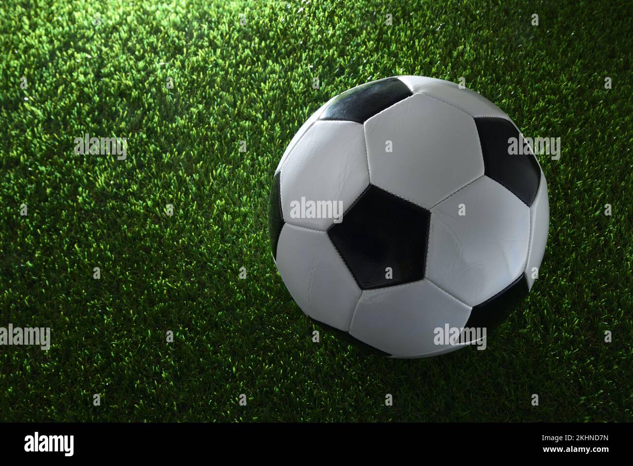 Klassischer Fußball auf Kunstrasen, beleuchtet durch einen Scheinwerfer. Draufsicht. Horizontale Zusammensetzung. Stockfoto
