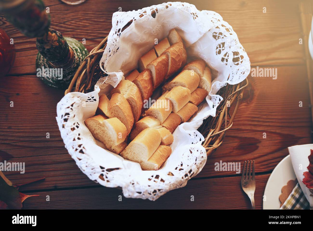 Brot, Speisen und Korb mit Vorspeise auf einem hölzernen Esstisch in einem Haus für eine Feier. Party, Mittagessen und Mutrition mit einem Baguette Stockfoto