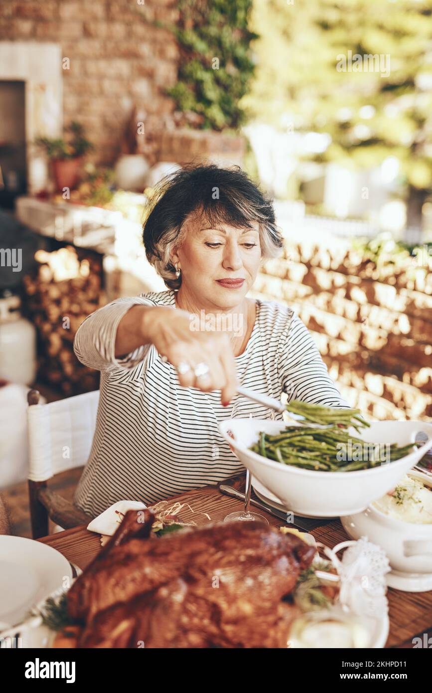 Abendessen, Gericht und Seniorin mit Essen bei einem Abendessen im Freien, einer Party oder einer Veranstaltung im Garten. Essen, Mittagessen und ältere Dame, die Gemüse serviert Stockfoto