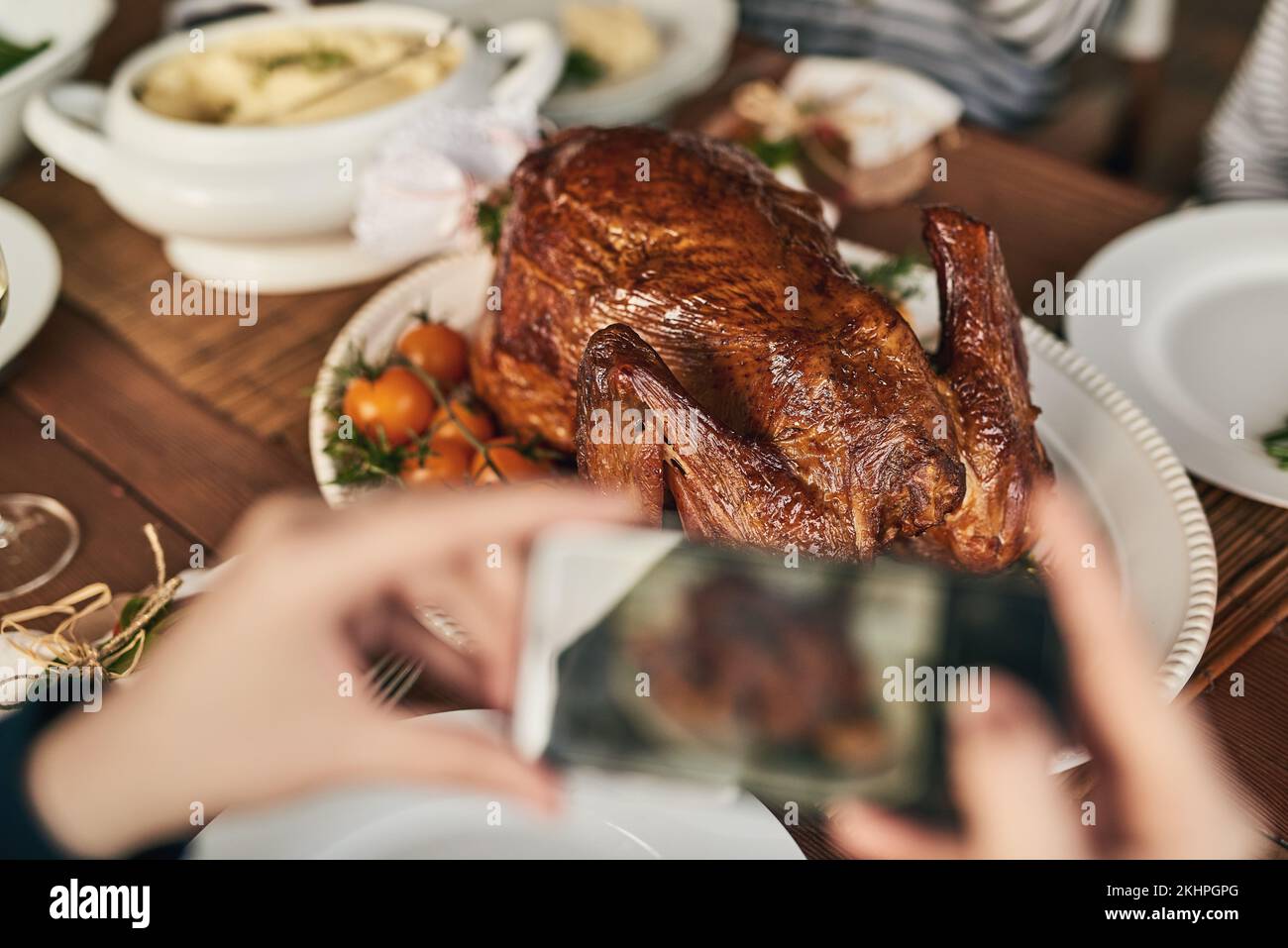 Hühnchen, Foto und Telefon mit Frau am Tisch für Essen, Blog und soziale Medien. Thanksgiving, Feier und festlich mit der Hand des Küchenchefs und Bild davon Stockfoto