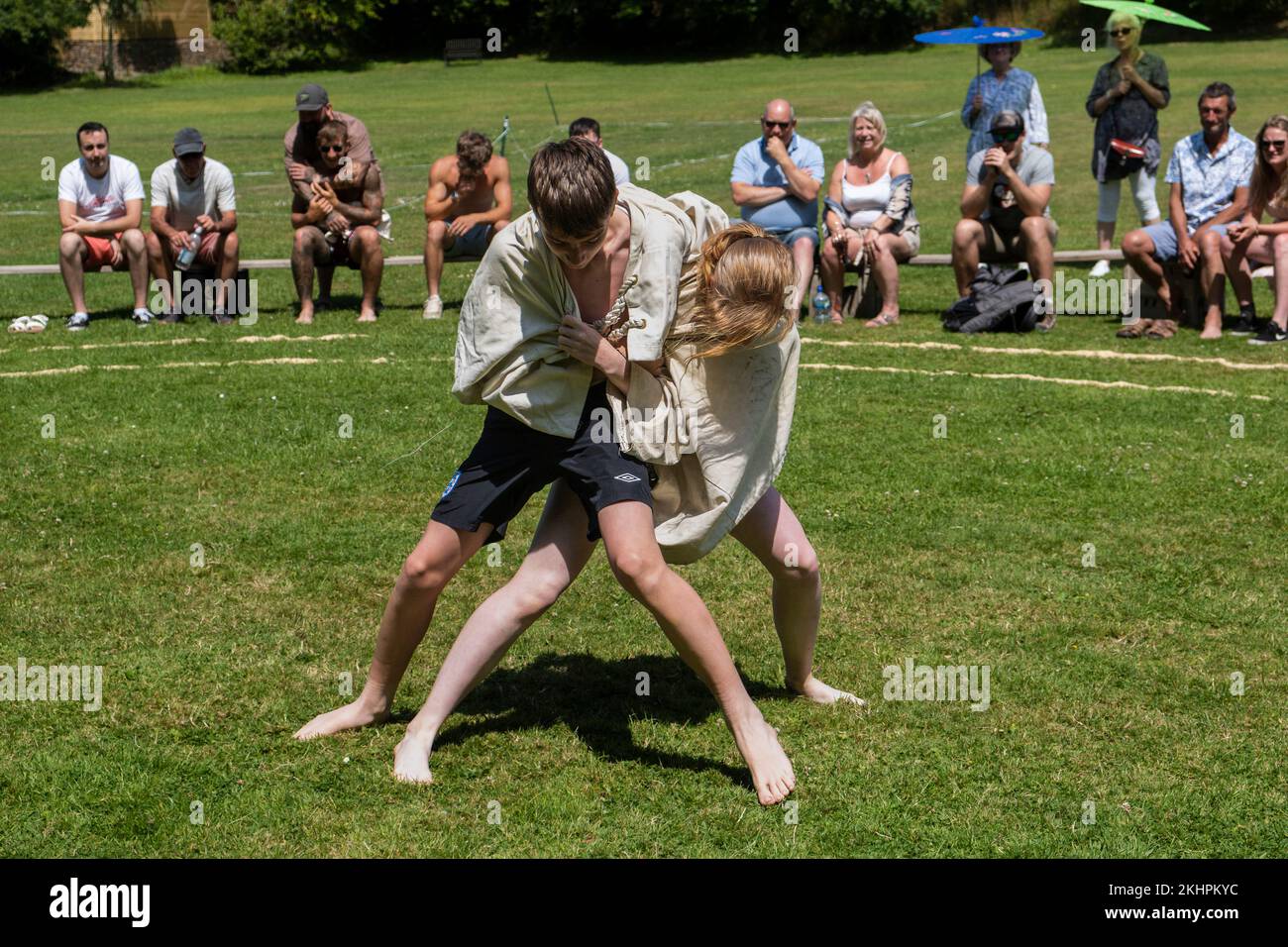 Ein junges Teenager-Mädchen, das mit einem Jungen kämpft, der beim Grand Cornish Wrestling Tournament auf dem malerischen Dorfgrün von St. Mawgan in Pydar i teilhat Stockfoto