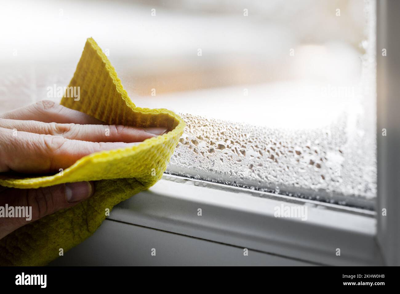 Hohe Luftfeuchtigkeit im Haus. Wischen Sie mit der Hand Kondenswasser von Plastikfenstern im Raum ab. Hausfeuchtigkeit Stockfoto