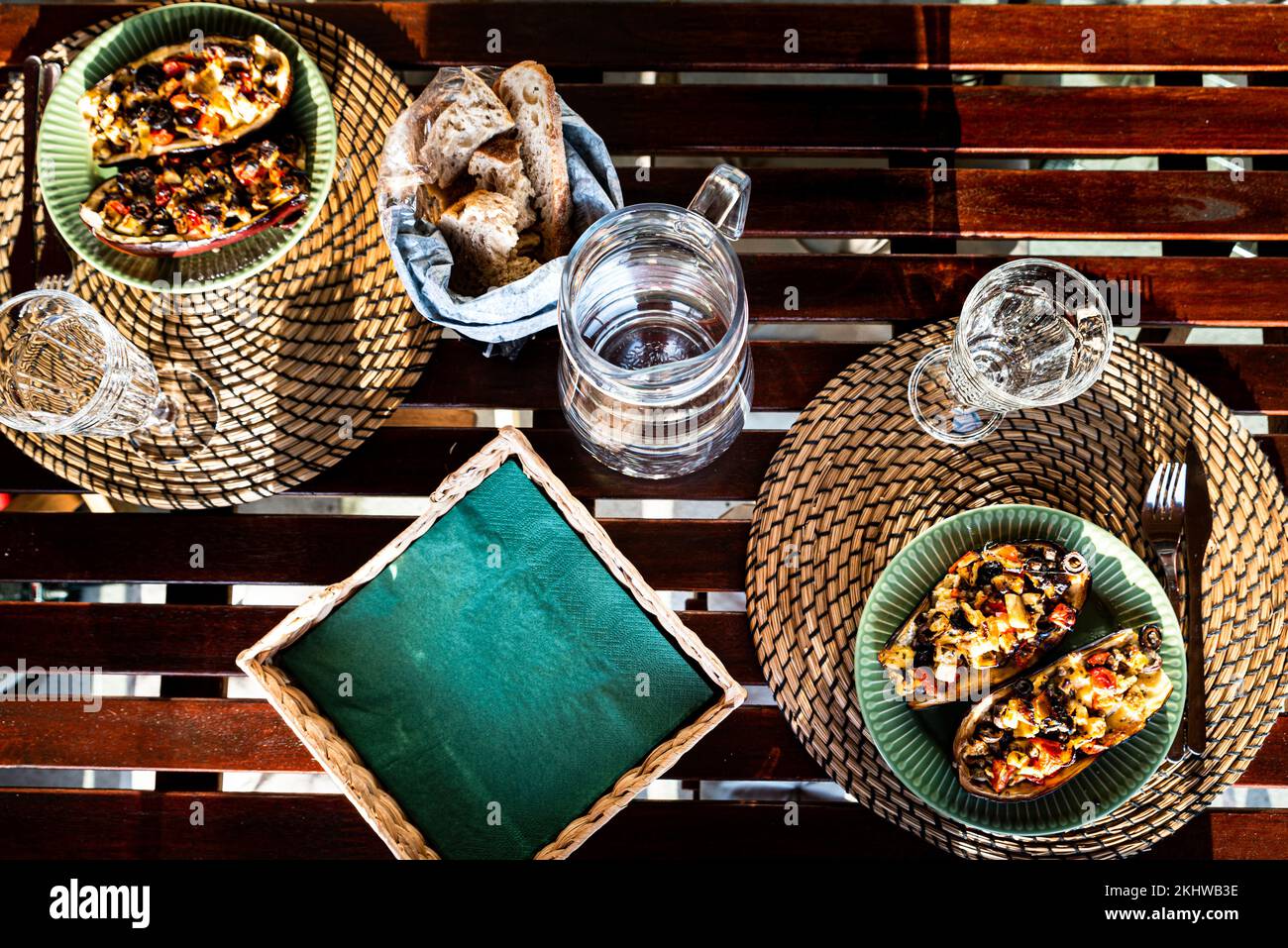 Rustikaler Tisch mit grünen Tellern gefüllter Auberginen oder Auberginen. Nahrhafte Aubergine oder Aubergine ist ein reichhaltiges Gericht, das Energie und Kalorien liefert Stockfoto