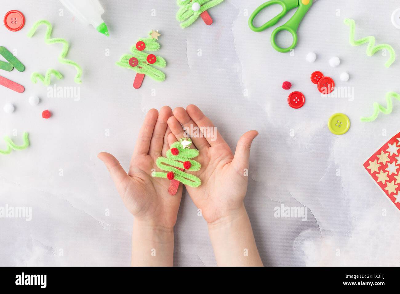 Das Kind macht eine Grußkarte Weihnachtscollage aus Papier. Mit seinen eigenen Händen gemacht. Kinderkunstprojekte für Kinder. Handwerk für Kinder. Draufsicht Stockfoto