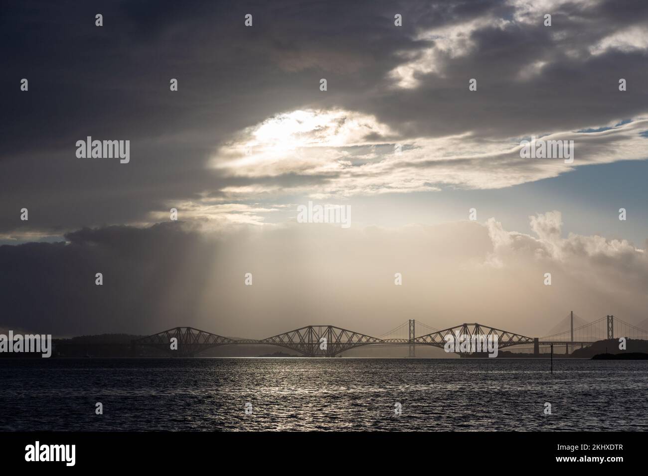 Die Three-Forth-Brücken werden von himmlischen Strahlen im Firth of Forth beleuchtet. Stockfoto