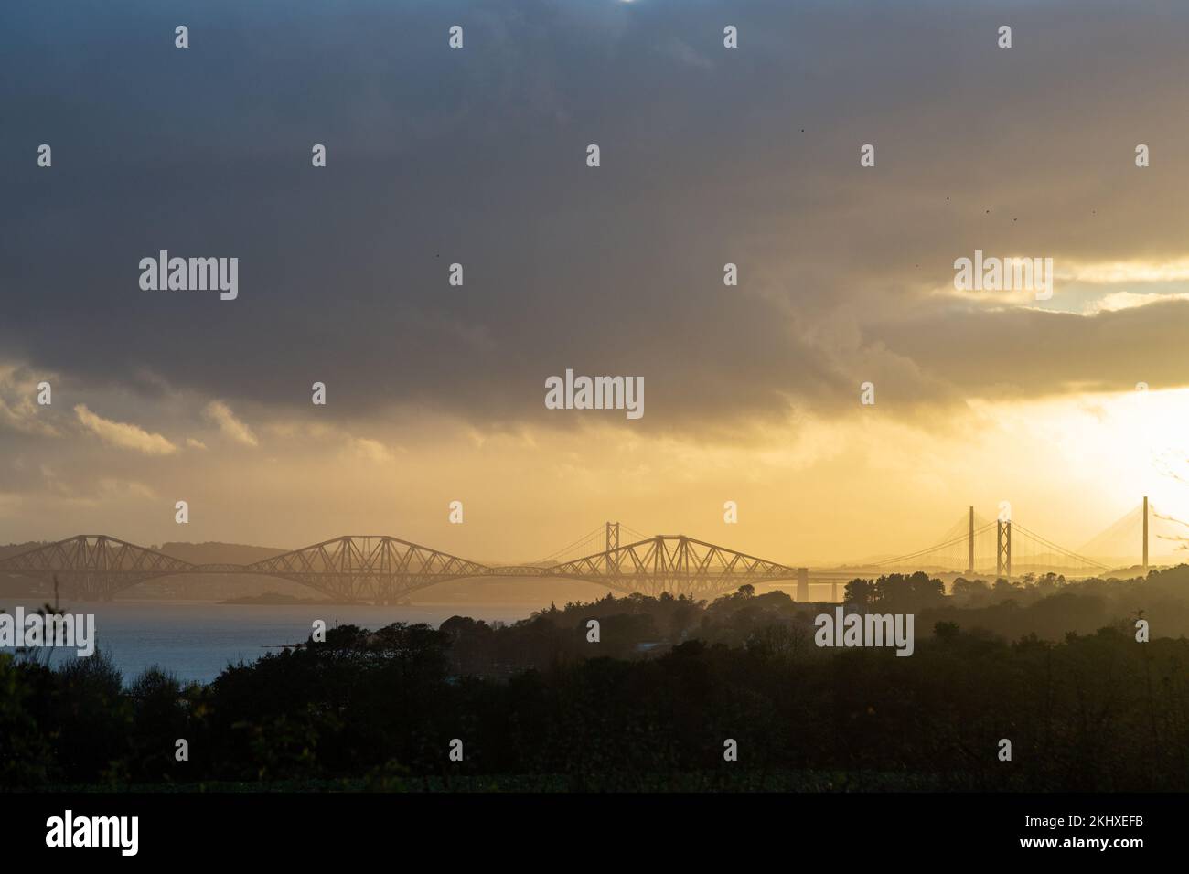 Alle drei Brücken über den Firth of Forth bei Sonnenuntergang von Dalgety Bay, Fife. Stockfoto