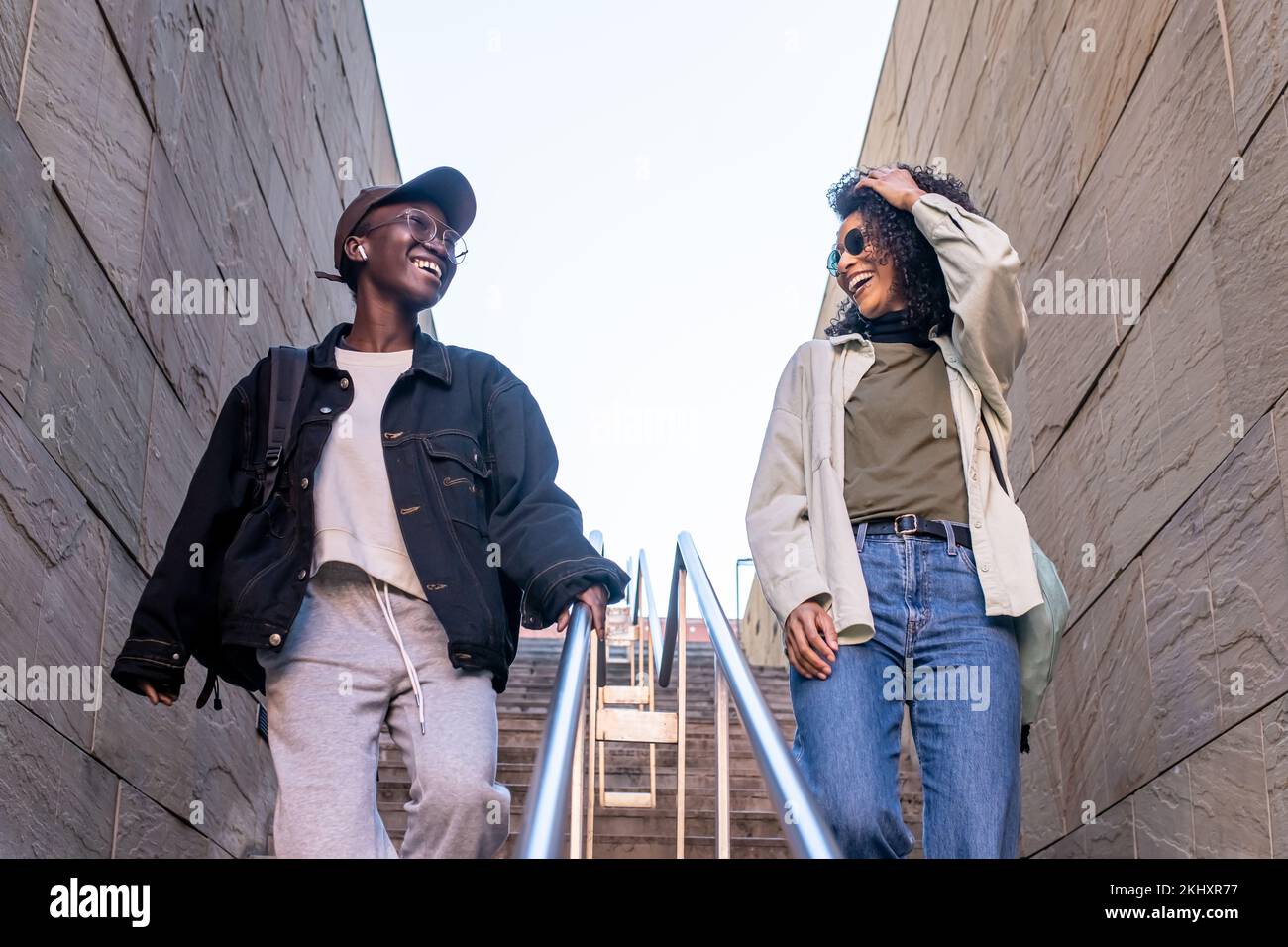 Zwei junge afroamerikanische Frauen, die in der Stadt spazieren gehen, weibliche beste Freunde, die sich unterhalten und lachen, Mode-Strett-Style-Leute, Generation z-Mädchen Stockfoto