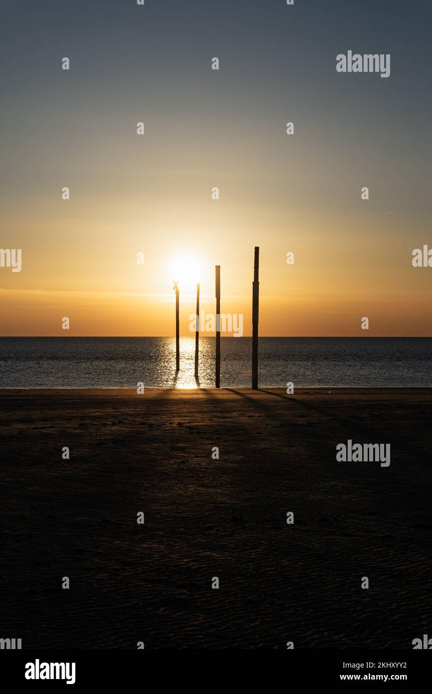 Eine vertikale Aufnahme der Reflexion der untergehenden Sonne auf dem Meer, Pole im Meer Stockfoto