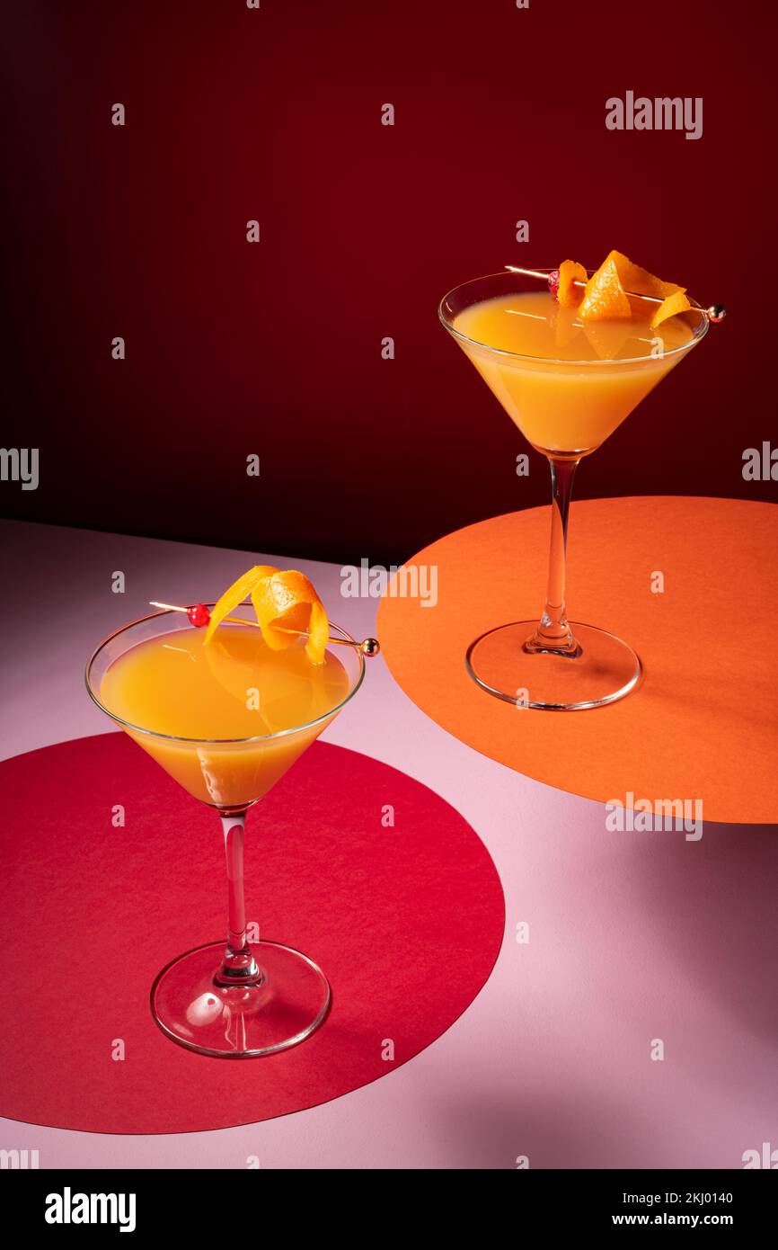 Wodka mit Orangensaftcocktail garniert mit Orangenschale auf dunkelrot Stockfoto