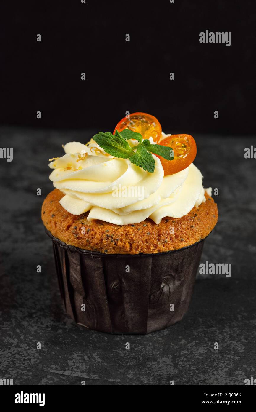 Cupcakes mit Käsesahne, dekoriert mit süßen Beeren auf dunklem Hintergrund. Layout für Design Stockfoto