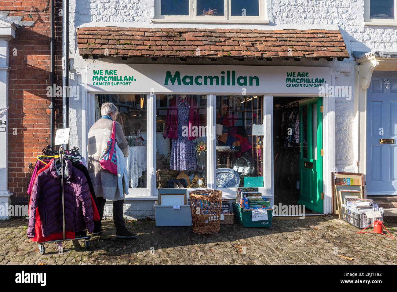 Eine Frau, die vor einem Macmillan Charity Shop in England einkauft Stockfoto