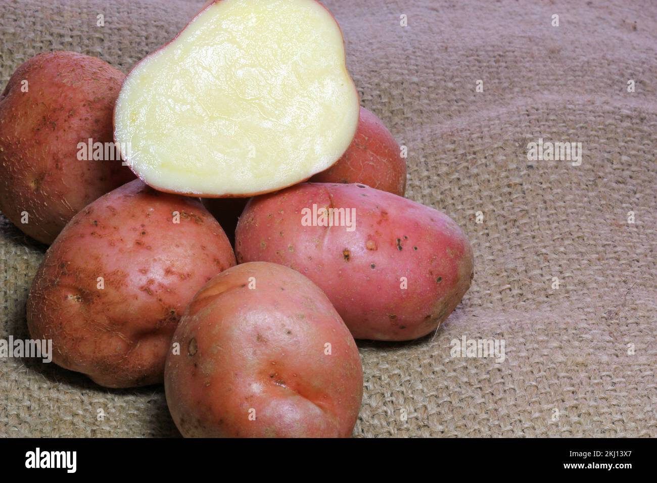 Rohe rote Kartoffeln mit hessischem Hintergrund, Kartoffeln in zwei Hälften geschnitten. Stockfoto