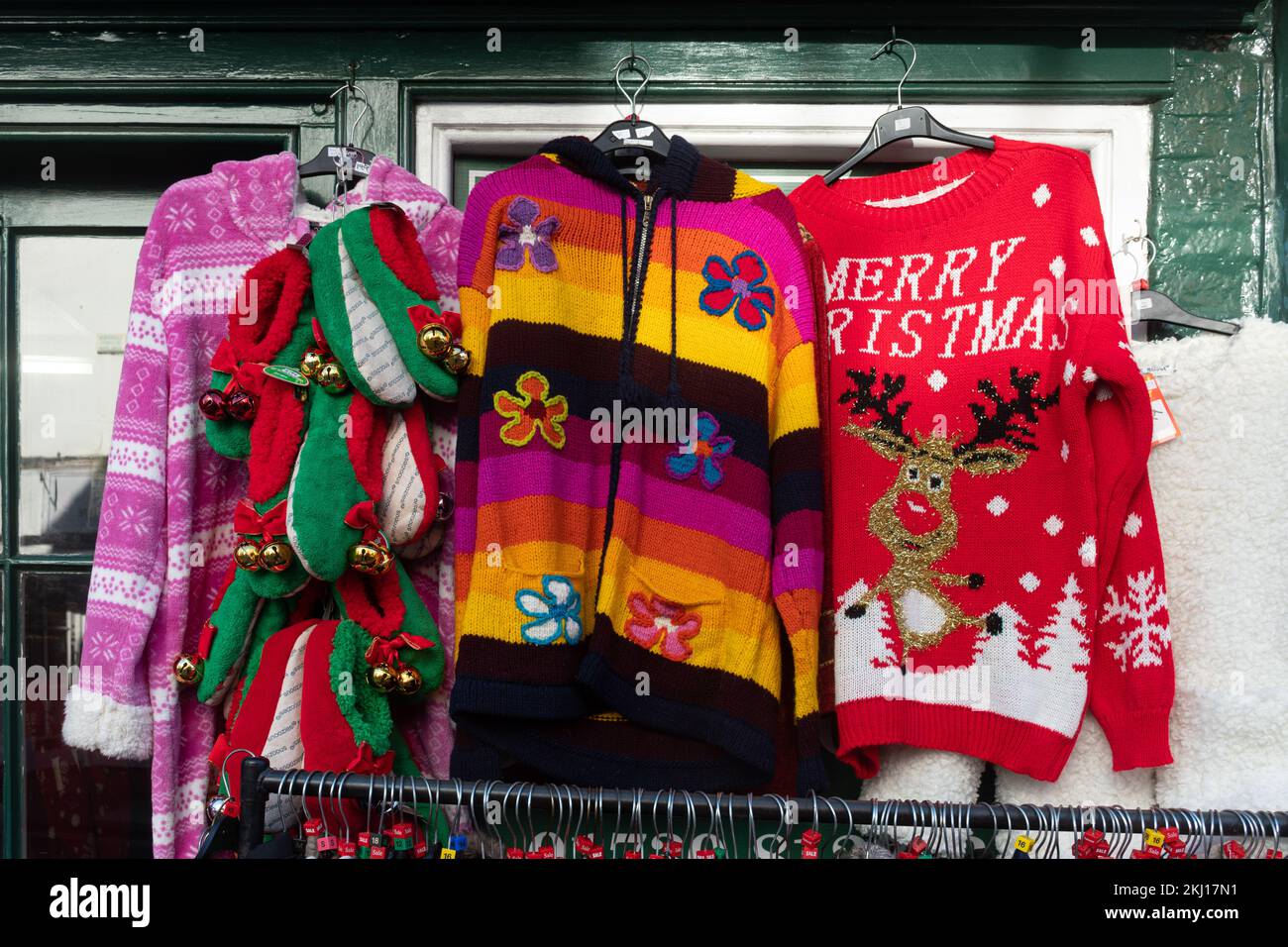 Weihnachtspullover, andere farbenfrohe Pullover und Snozies Hausschuhe, die vor einem Geschäft in England ausgestellt werden Stockfoto